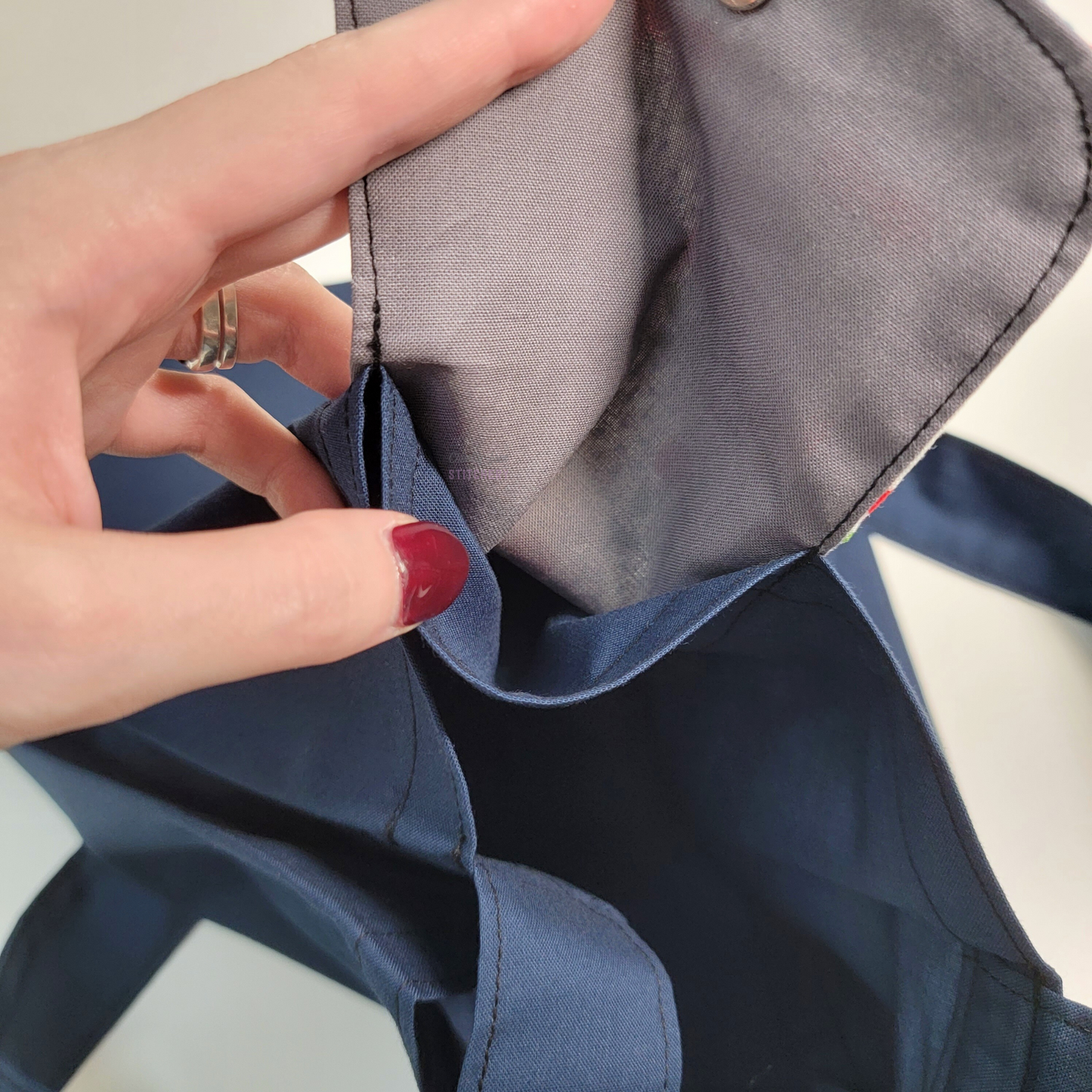 Inside of the foldable tote bag, a hidden pocket underneath the flap.