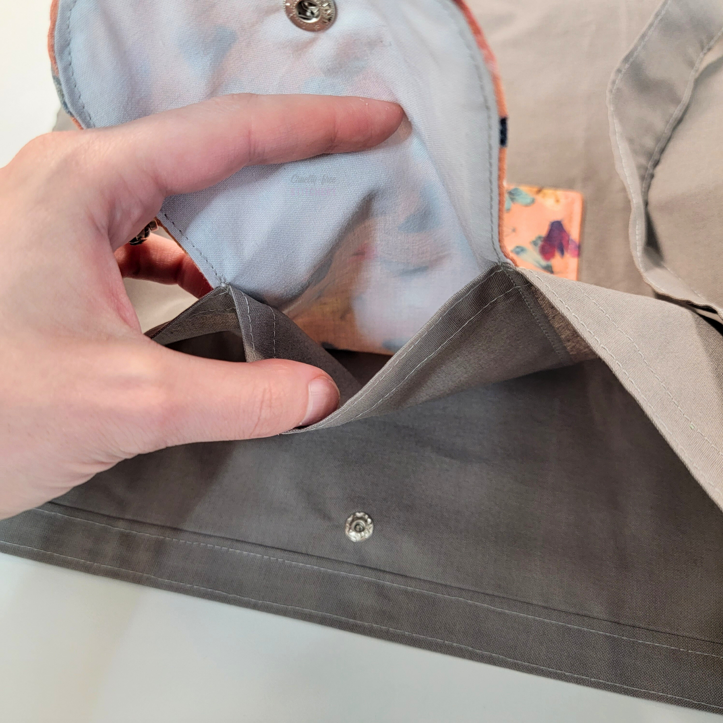 Inside of the foldable tote bag, a hidden pocket underneath the flap.