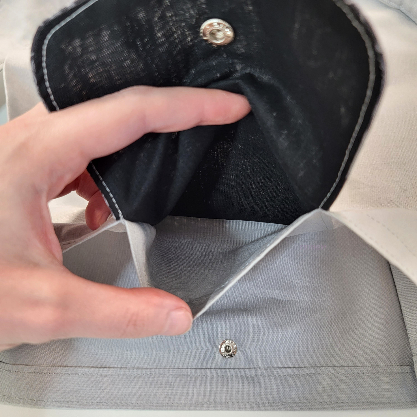 Inside of the foldable tote bag, a hidden pocket underneath the flap.