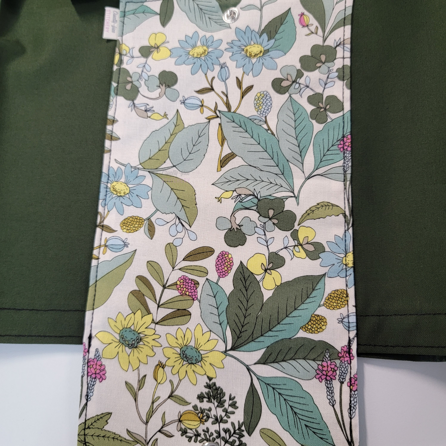 Close-up of the sketched plants - some various leaves, flowers, and ferns with greens, pale yellow, and pink.