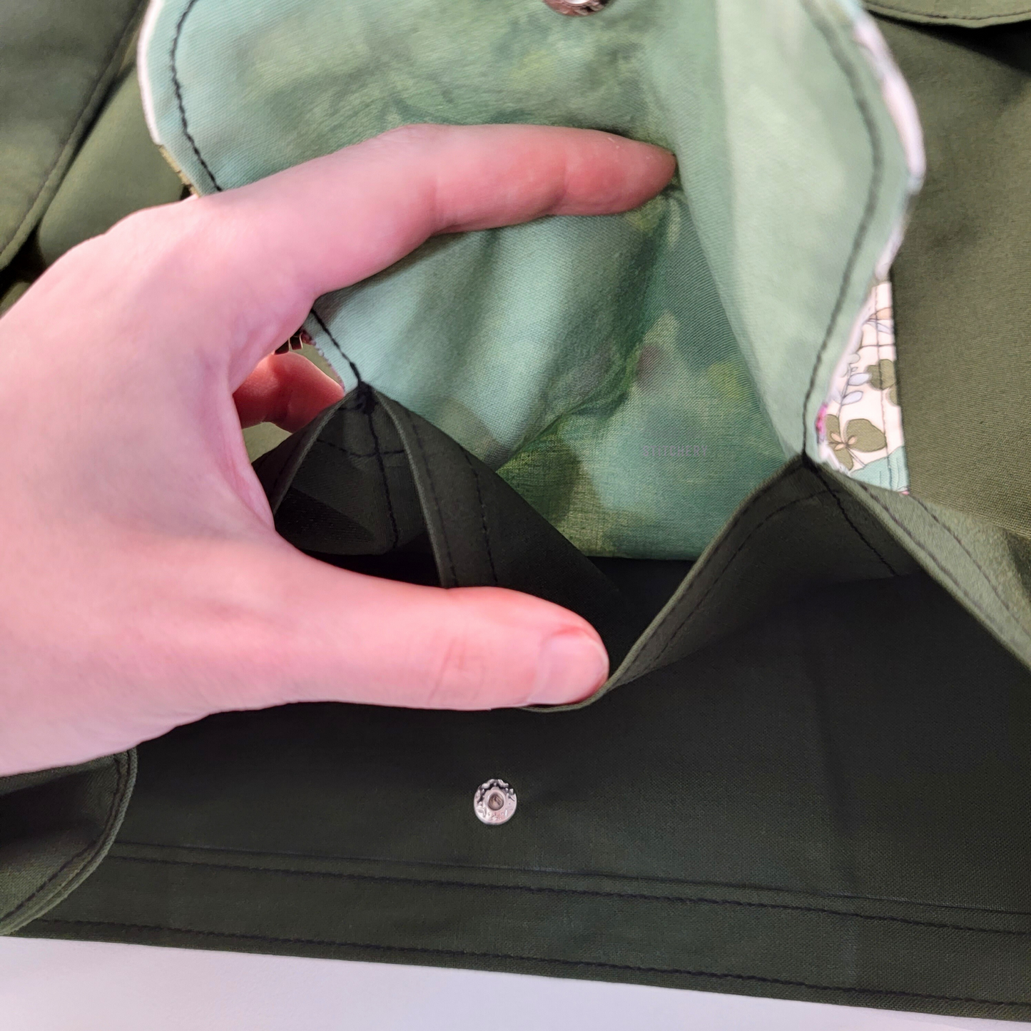 Inside of the foldable tote bag, a hidden pocket underneath the flap.