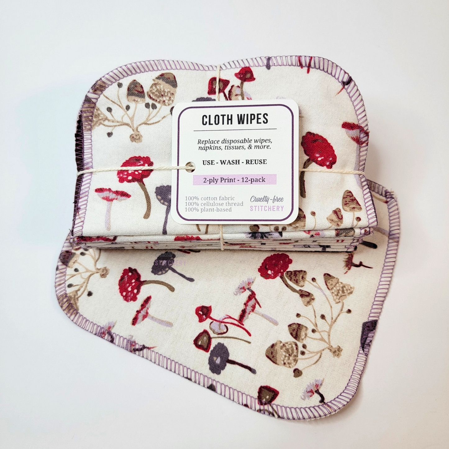 A bundled pack of the cloth wipes, tied with cotton string and a small tag, laid on top of a separate cloth wipe.
