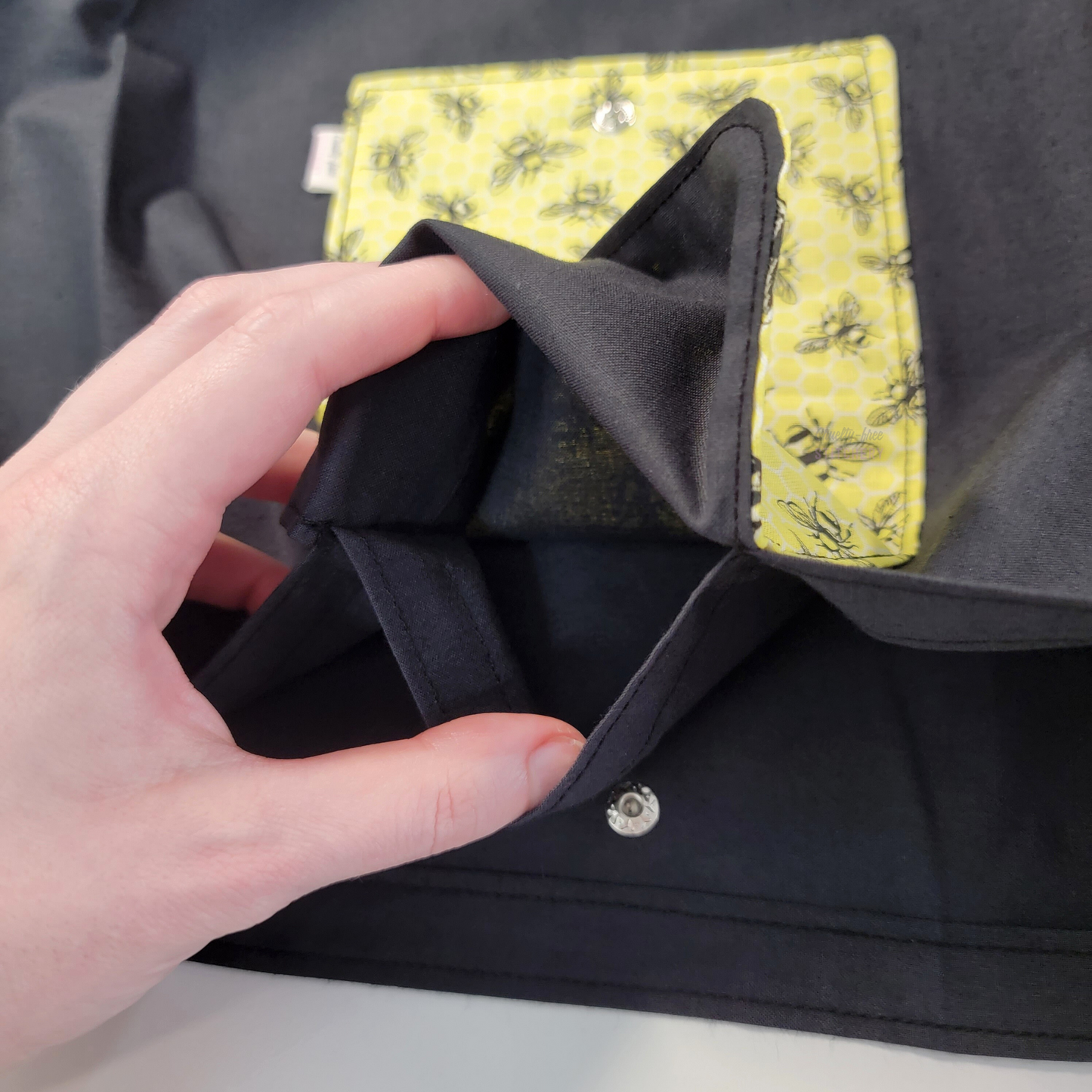 Inside of the foldable tote bag, a hidden pocket underneath the flap.