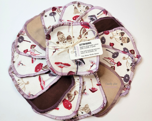 The mushrooms print cotton rounds arranged in a circle, with a bundled pack in the center. The print is white with wild mushrooms in various shades of reds, purples, and browns. This picture shows some with tan and dark brown on the back.