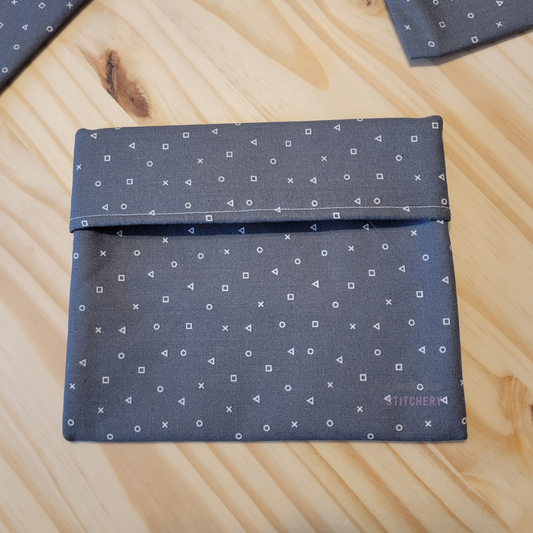 Fold-over style snack bag, gray with game shapes print.