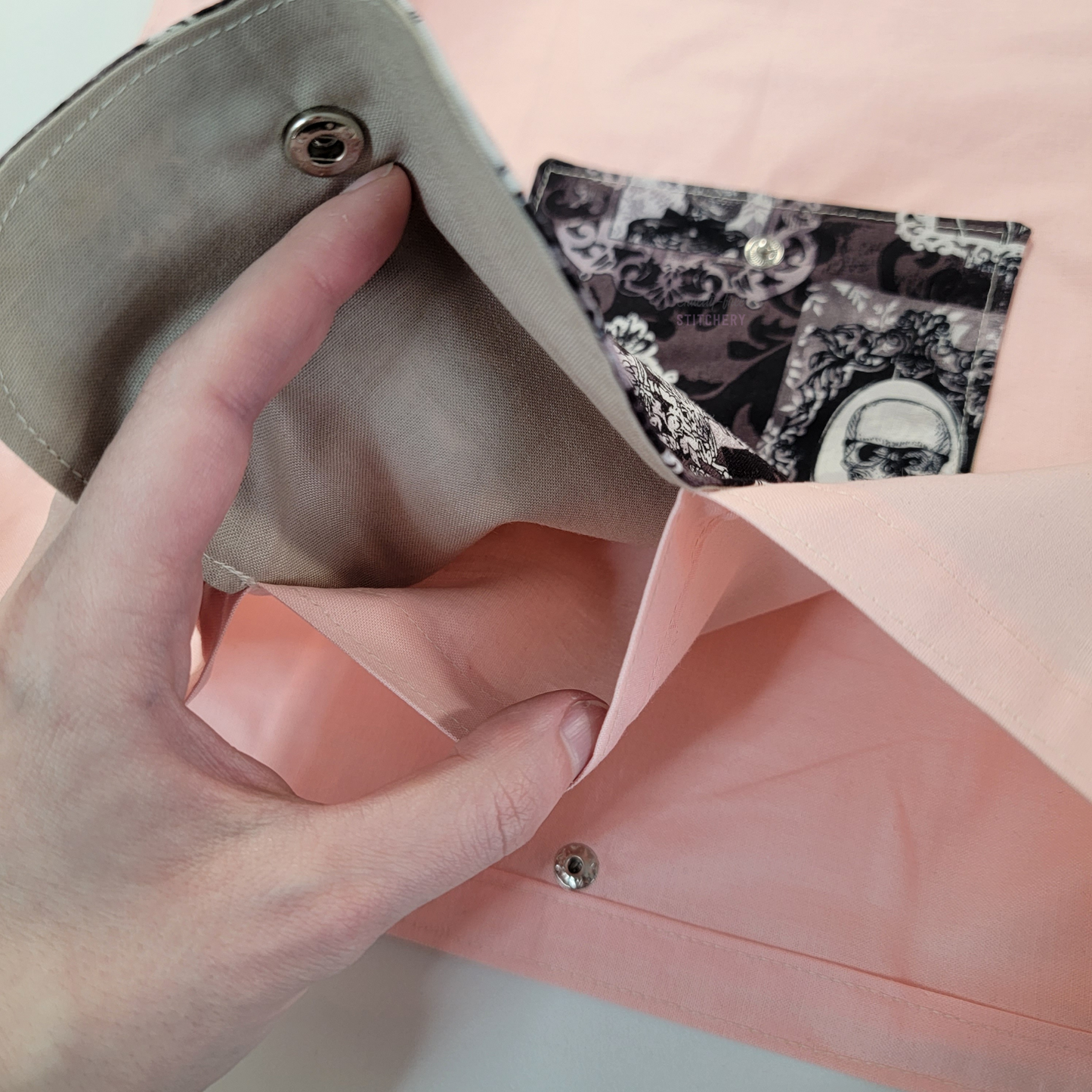 Inside of the foldable tote bag, a hidden pocket underneath the flap.