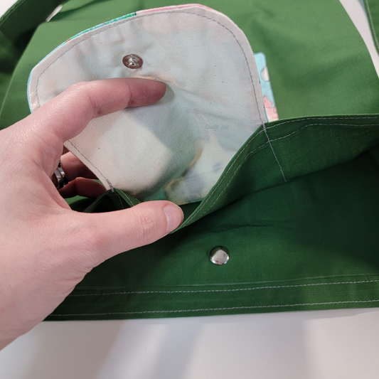 Inside of the foldable tote bag, a hidden pocket underneath the flap.
