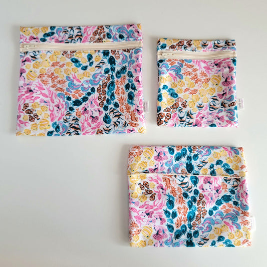 Three Reef Reusable Snack Bags arranged separately to show the difference between sizes. Large Zip is not quite double the size of the Small Zip, and the Foldover is slightly smaller than the Large Zip.