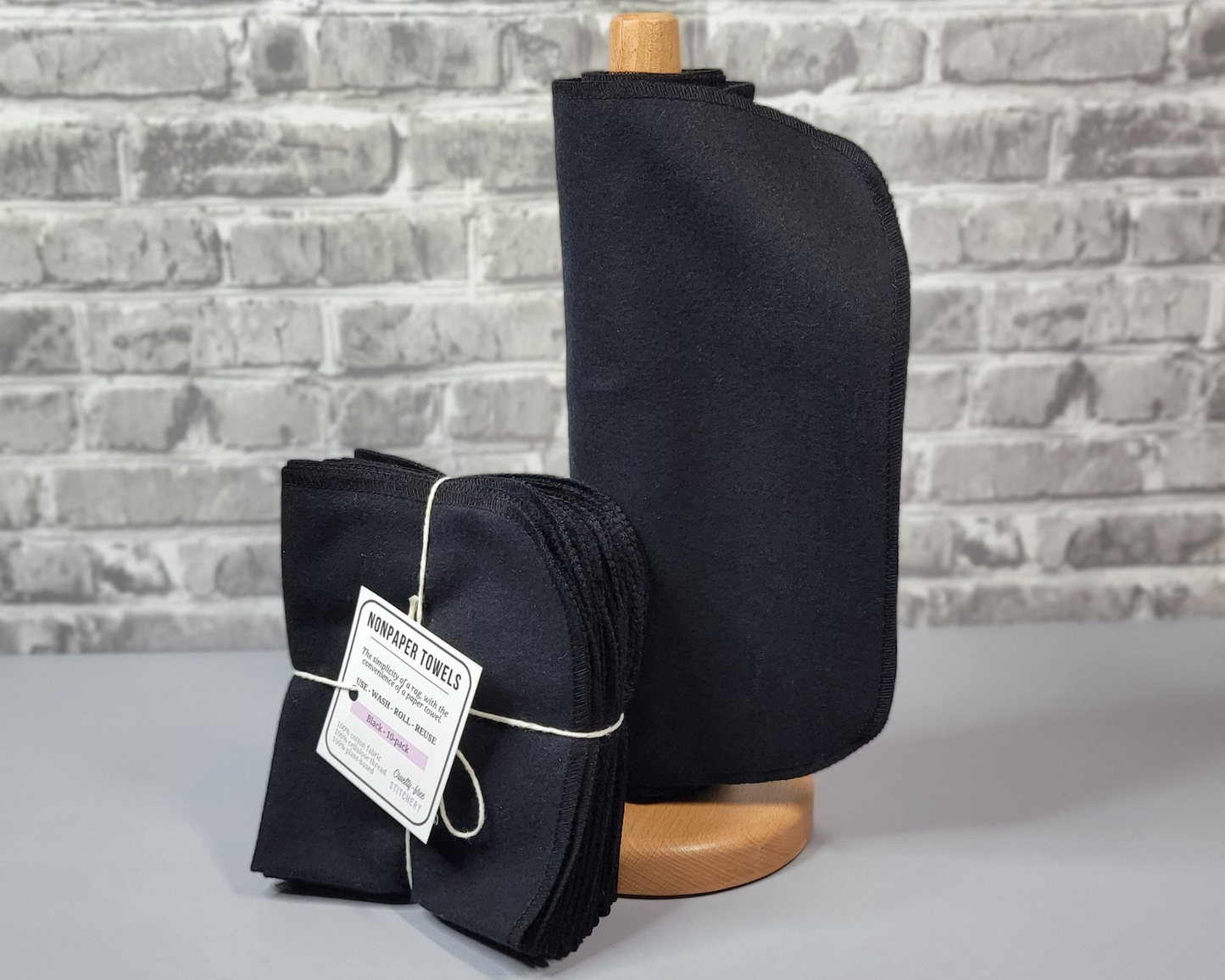 Black NonPaper Towels on a wooden roll next to a bundled pack that is tied with string and a small tag.
