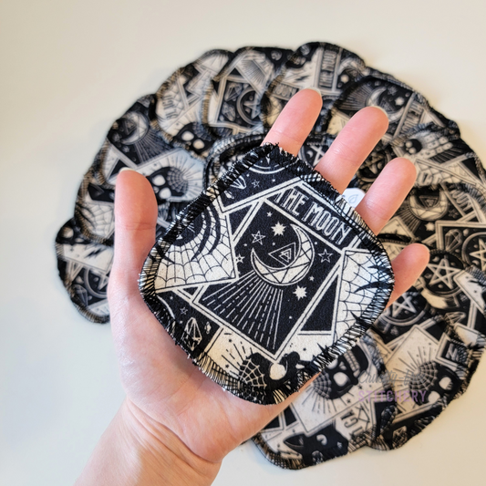 A tarot cards print reusable cotton round in my open hand to show the size. It is slightly bigger than my palm, or approximately 4x4".