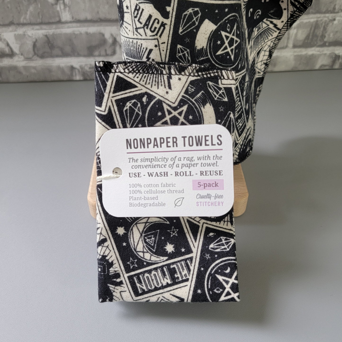 Close-up of the 5-pack, the tag reads "nonpaper towels, the simplicity of a rag with the convenience of a paper towel. Use wash roll reuse. 100% cotton fabric, 100% cellulose thread, plant-based, biodegradable. 5-pack, cruelty-free stitchery."