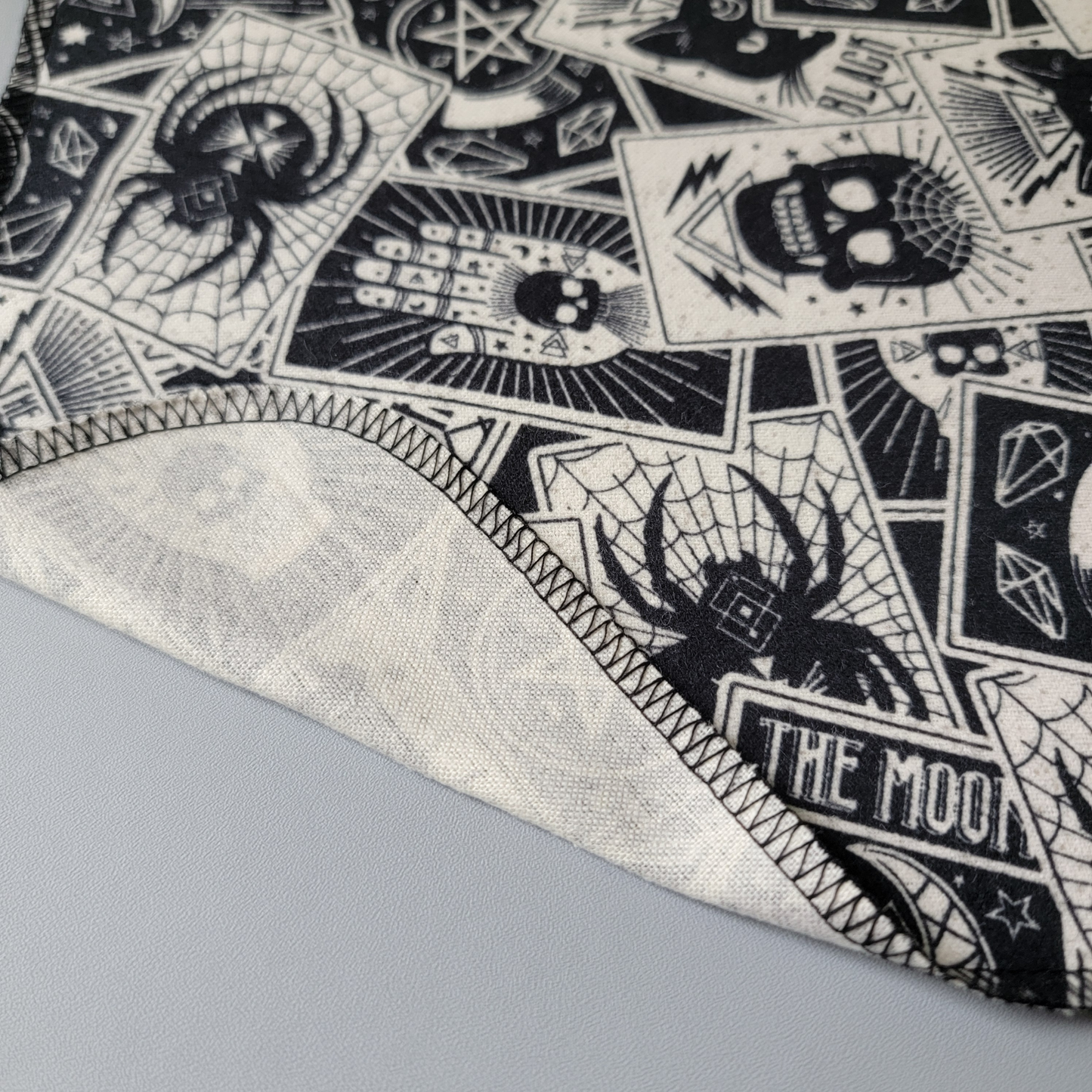 A close-up of the tarot nonpaper towel with an edge folded back to show that there is one layer of fabric and the back is unprinted off-white.
