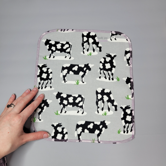 Cow print NonPaper Towel laid flat next to my hand for size reference.