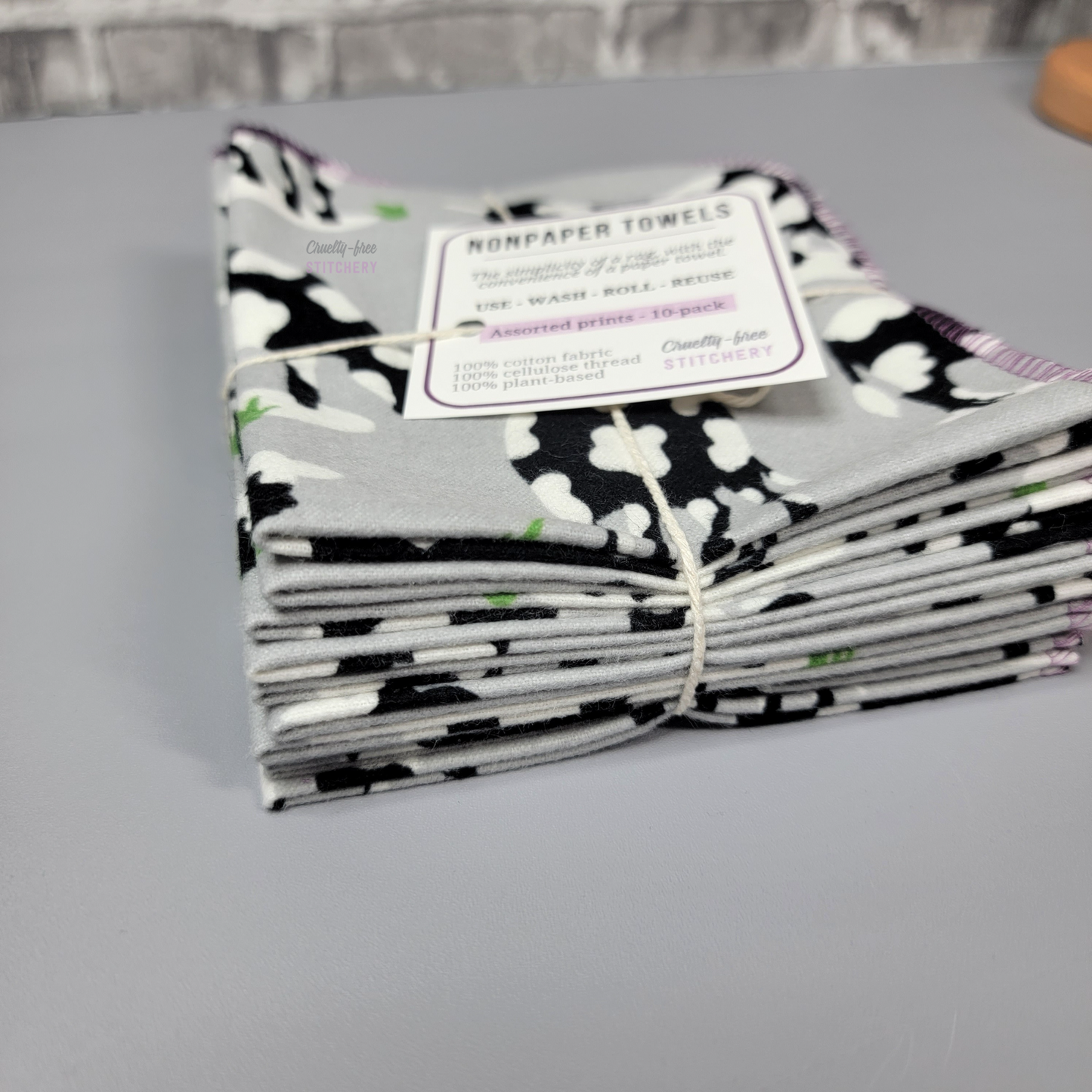 A stack of the grey cows print NonPaper Towels, bundled in cotton twine like a gift.