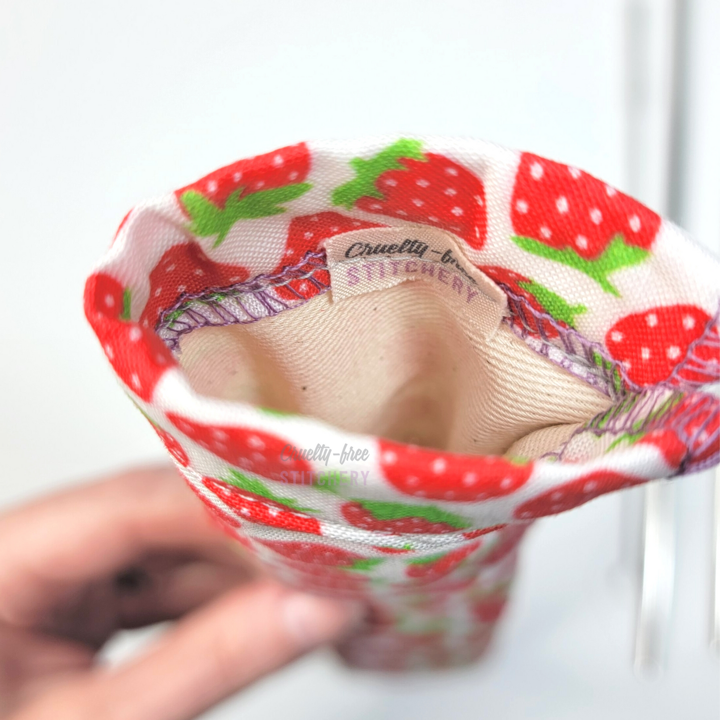 Reusable straw pouch viewed from the top down to show the inside. There is a tiny white tag with the Cruelty-Free Stitchery logo, and a natural-color lining.