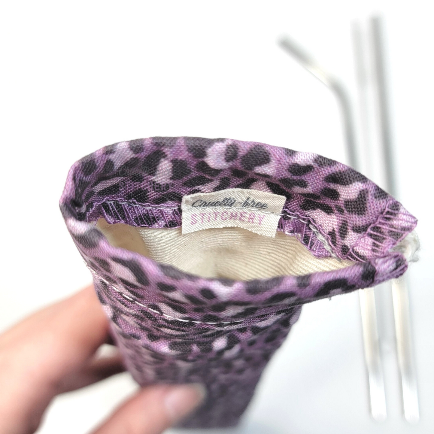 Reusable straw pouch viewed from the top down to show the inside. There is a tiny white tag with the Cruelty-Free Stitchery logo, and a natural-color lining.
