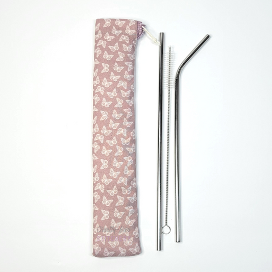 Reusable straw pouch in the same pink butterflies print laying vertically next to a straw cleaner brush, a straight stainless steel straw, and a bent stainless steel straw.
