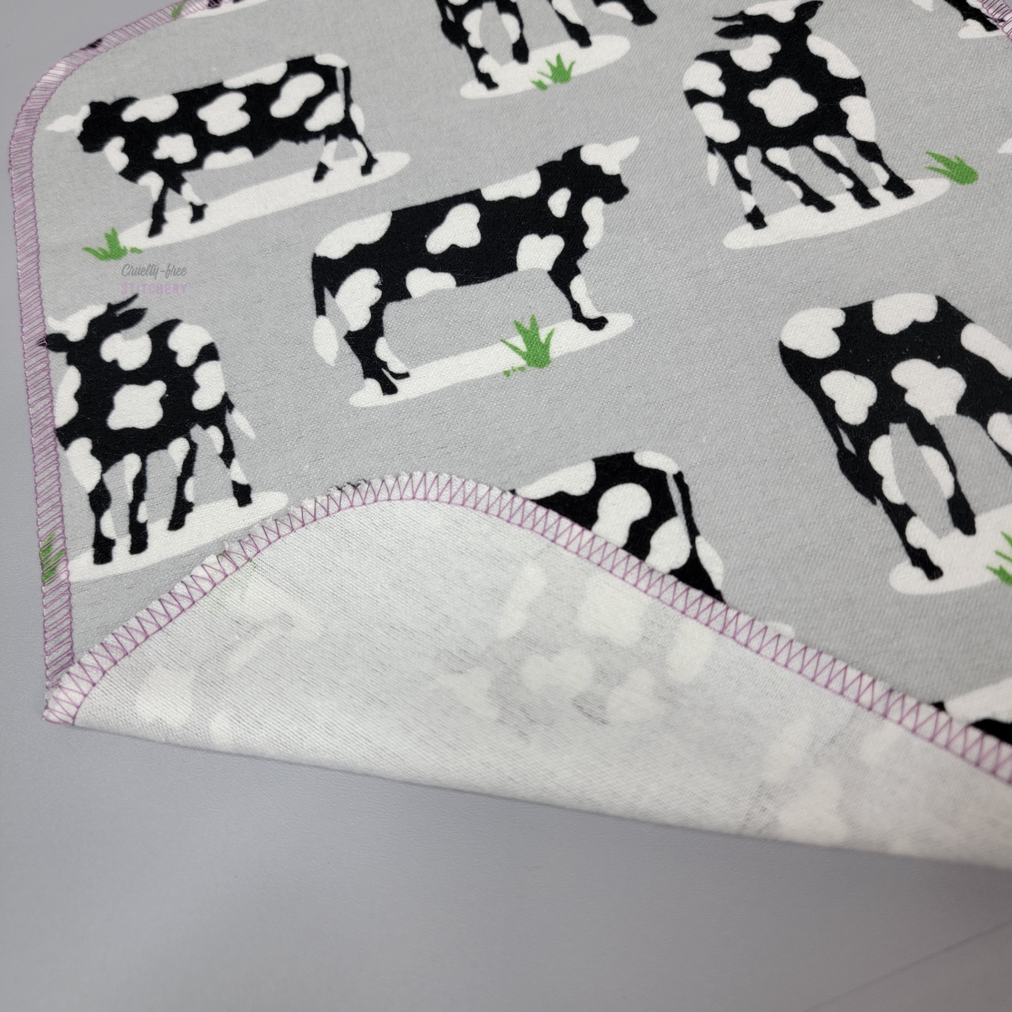The corner of a cow print NonPaper Towel with the end folded up to show the back side, which is unprinted solid white.