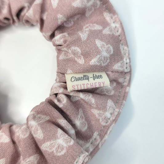 Close-up of the scrunchie with a small white tag with the Cruelty-Free Stitchery logo.