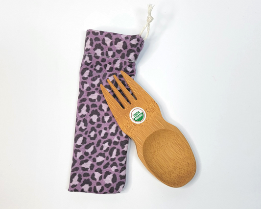 Reusable bamboo spork with pouch. The pouch is a muted violet leopard print. The pouch is sitting diagonally with the spork partially on top pointing the other way. The spork is small, a double ended fork and spoon.