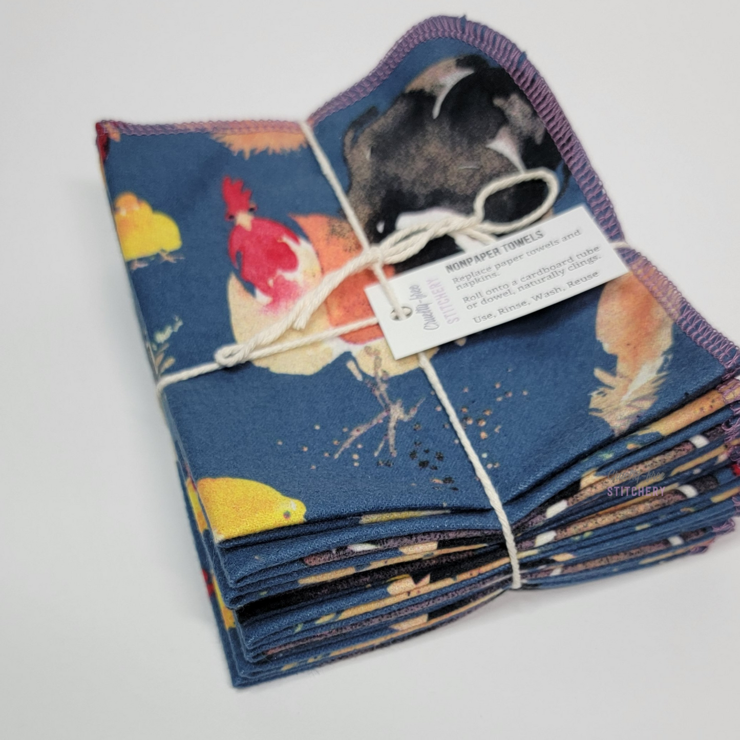 A 10-pack of the Blue Chickens NonPaper Towels, tied with string, shown from a low angle to see there are ten towels in the bundle.
