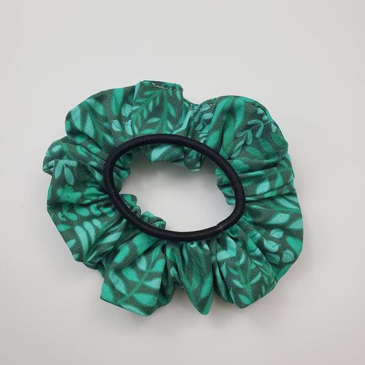Green leaves scrunchie shown with a regular black hair tie on top for size reference.