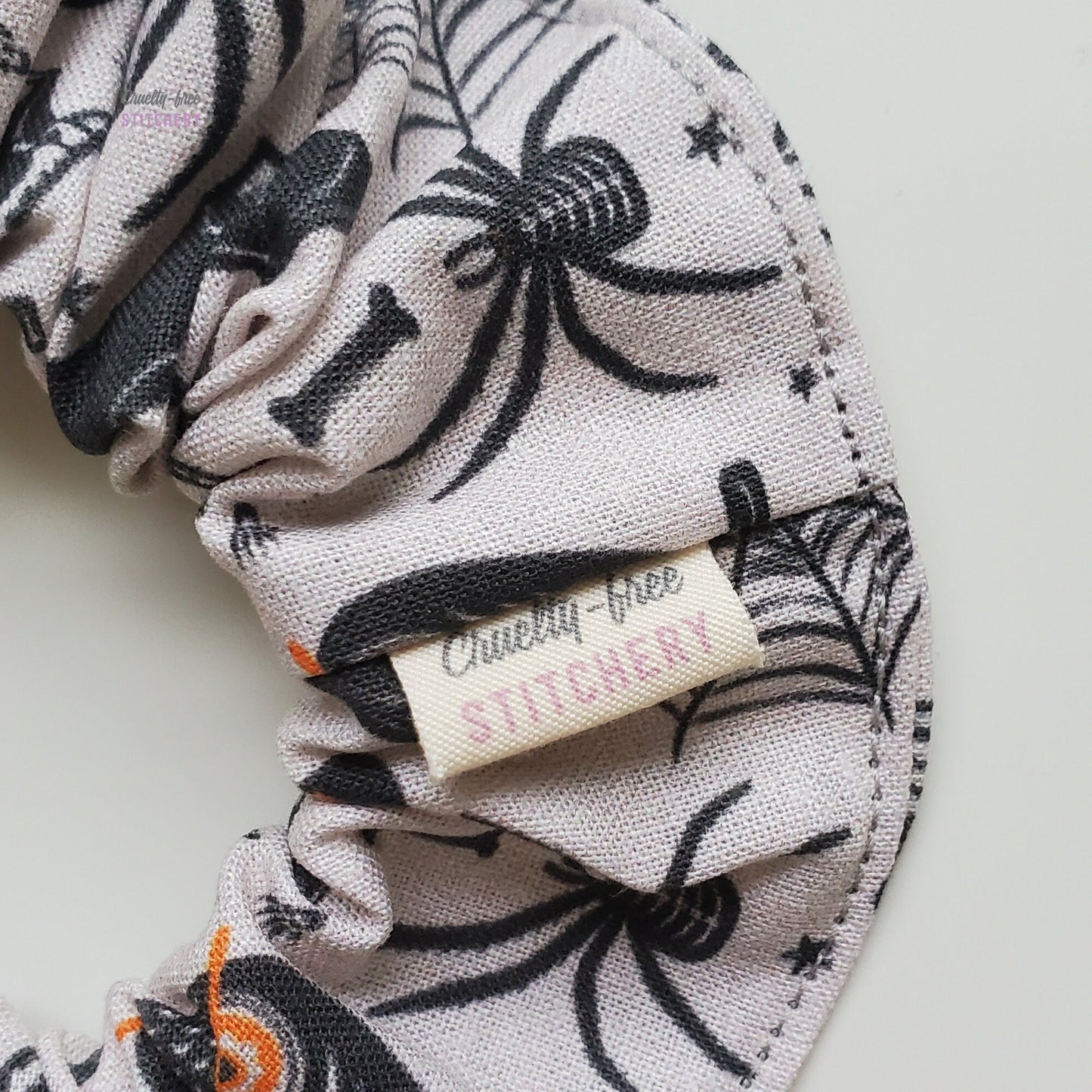 Close-up of the scrunchie with a small white tag with the Cruelty-Free Stitchery logo.