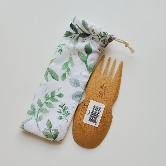 Reusable spork pouch laying diagonally next to an upside-down bamboo spork.