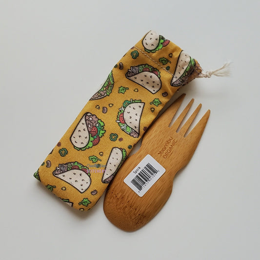 Reusable spork pouch laying diagonally next to an upside-down bamboo spork.