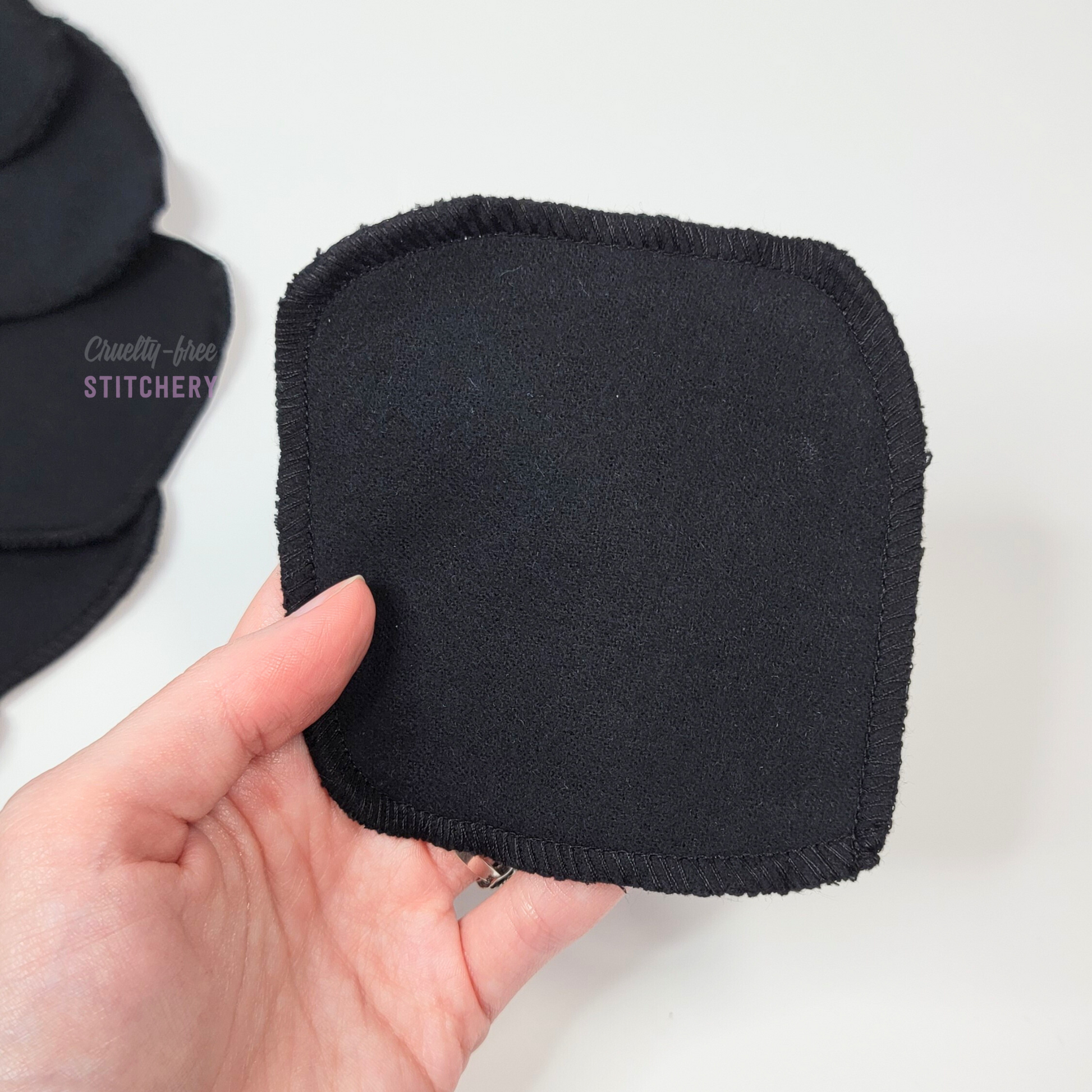 A black reusable cotton round in my hand to show the size. They are larger than a regular disposable cotton round.