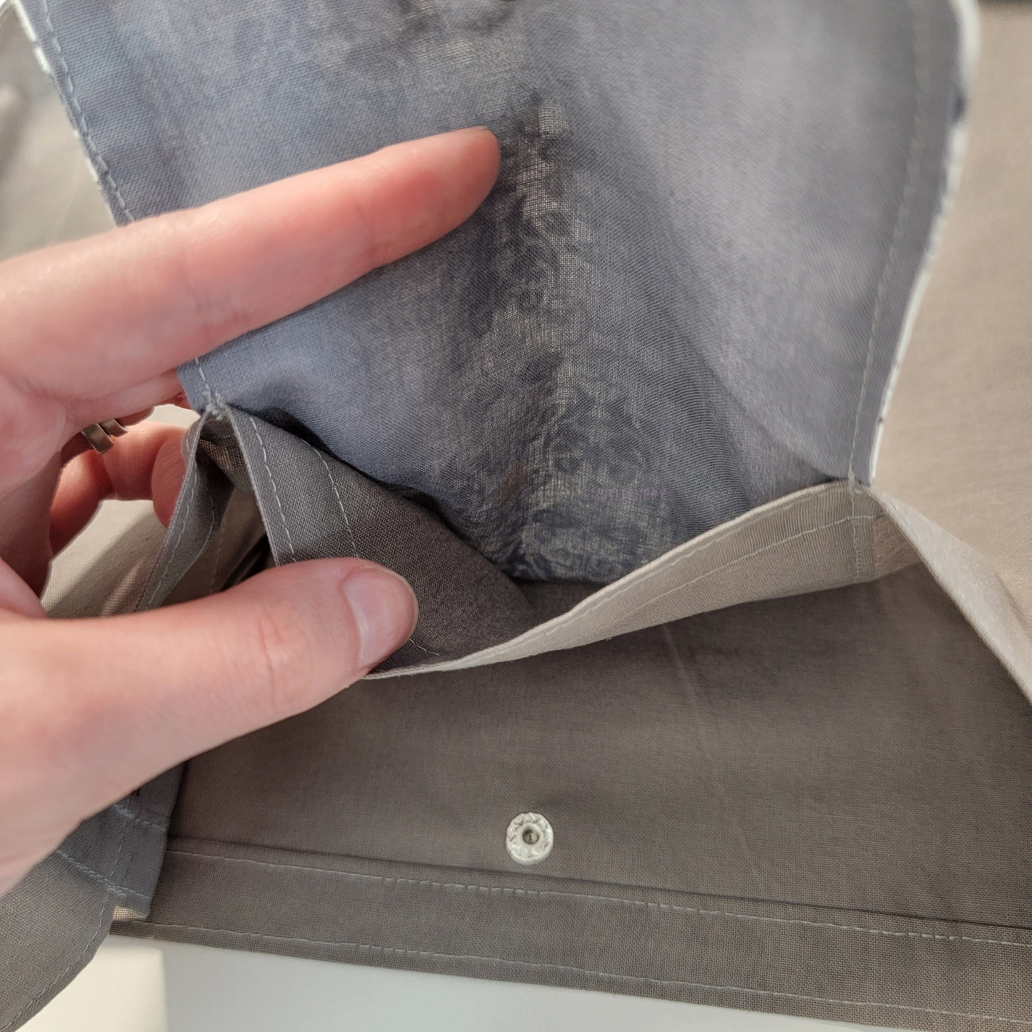 Inside of the foldable tote bag, a hidden pocket underneath the flap.