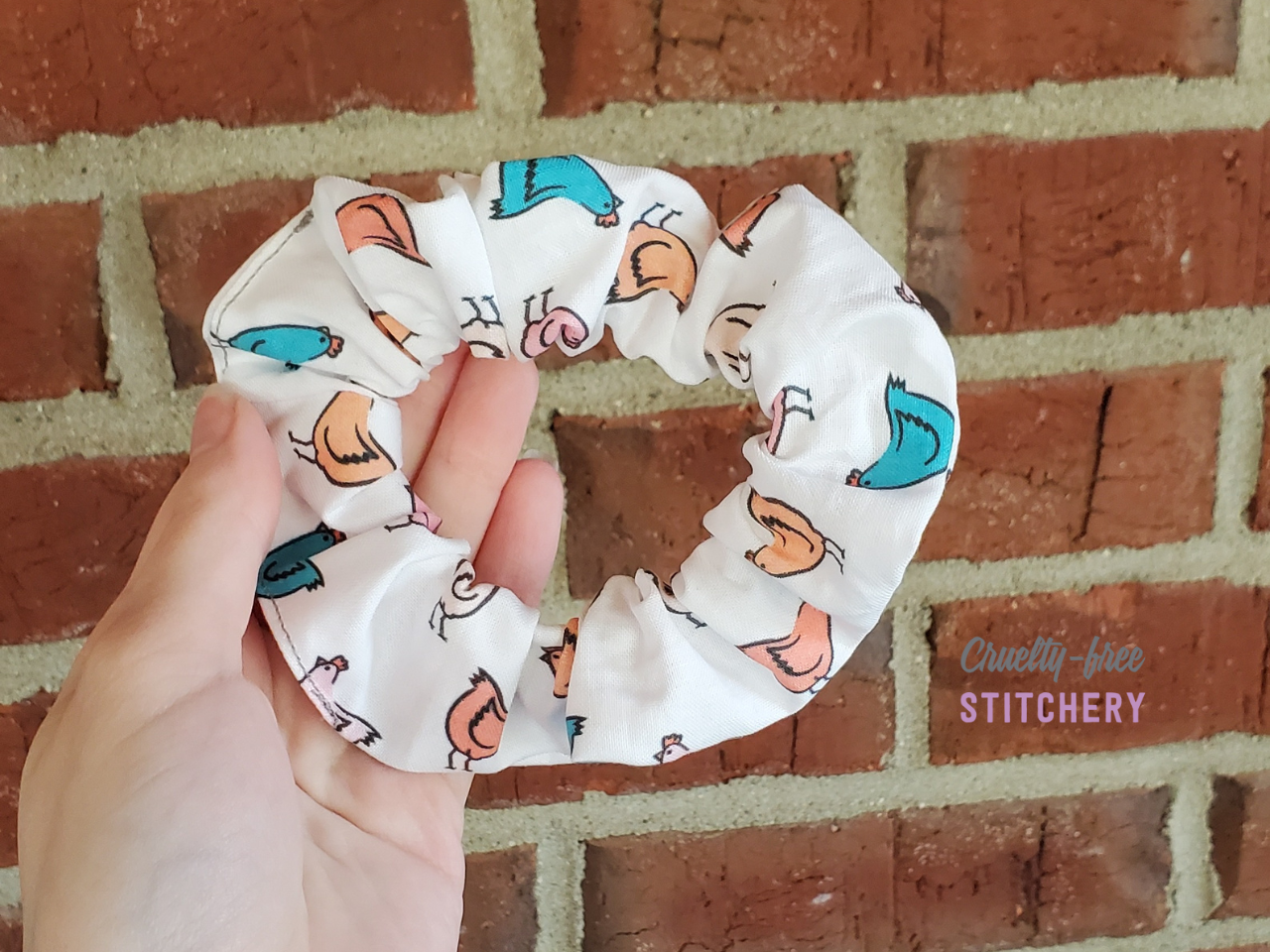 White scrunchie with teal, orange, light pink, and light orange chickens.