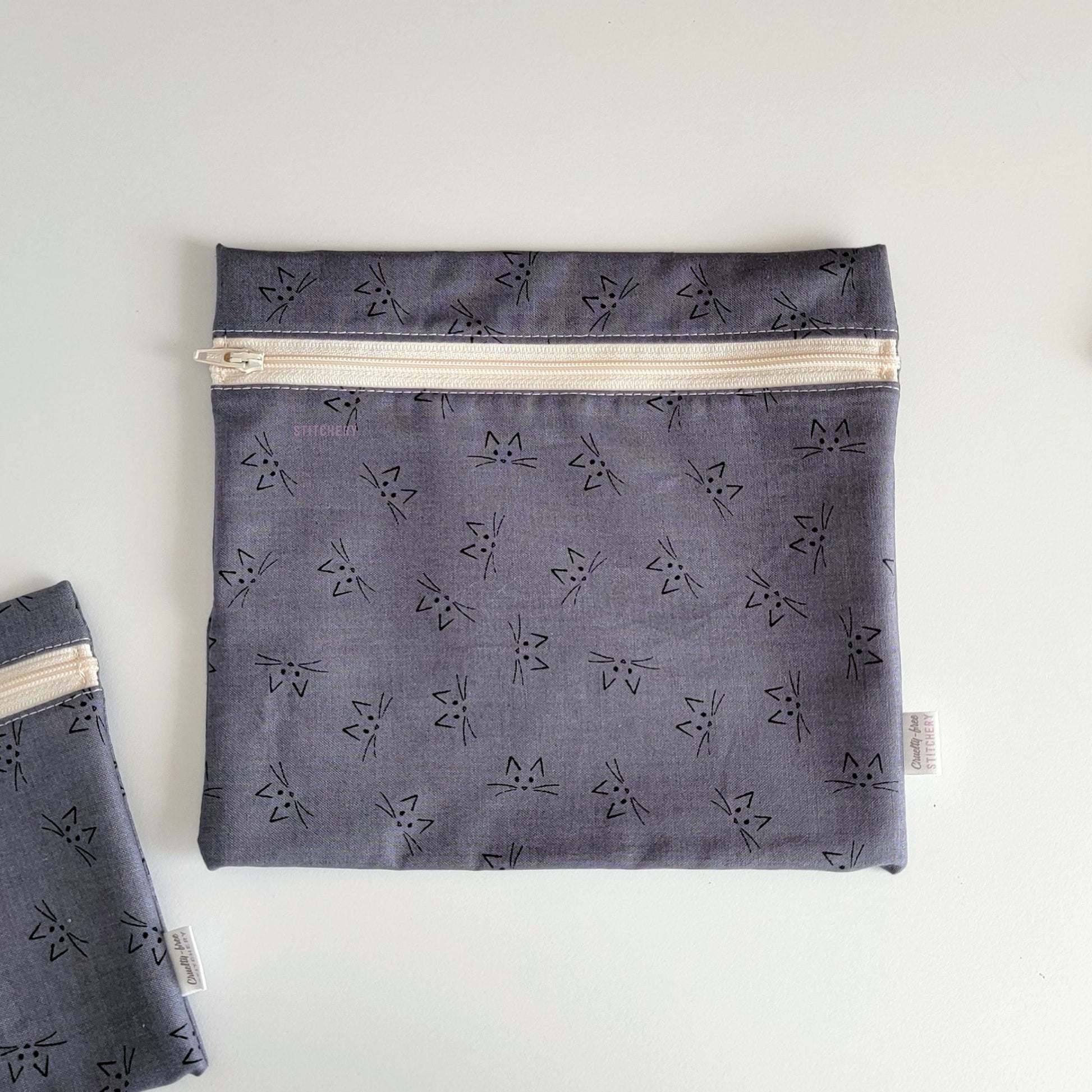 The Gray Cat Face Large Zip Reusable Snack Bag, shown closed with two other bags barely visible on the edges of the photo. 