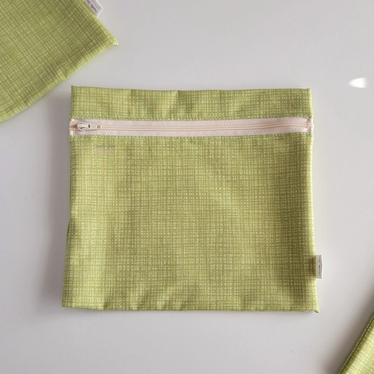 The light green texture Large Zip Reusable Snack Bag, shown closed with two other bags barely visible on the edges of the photo. 