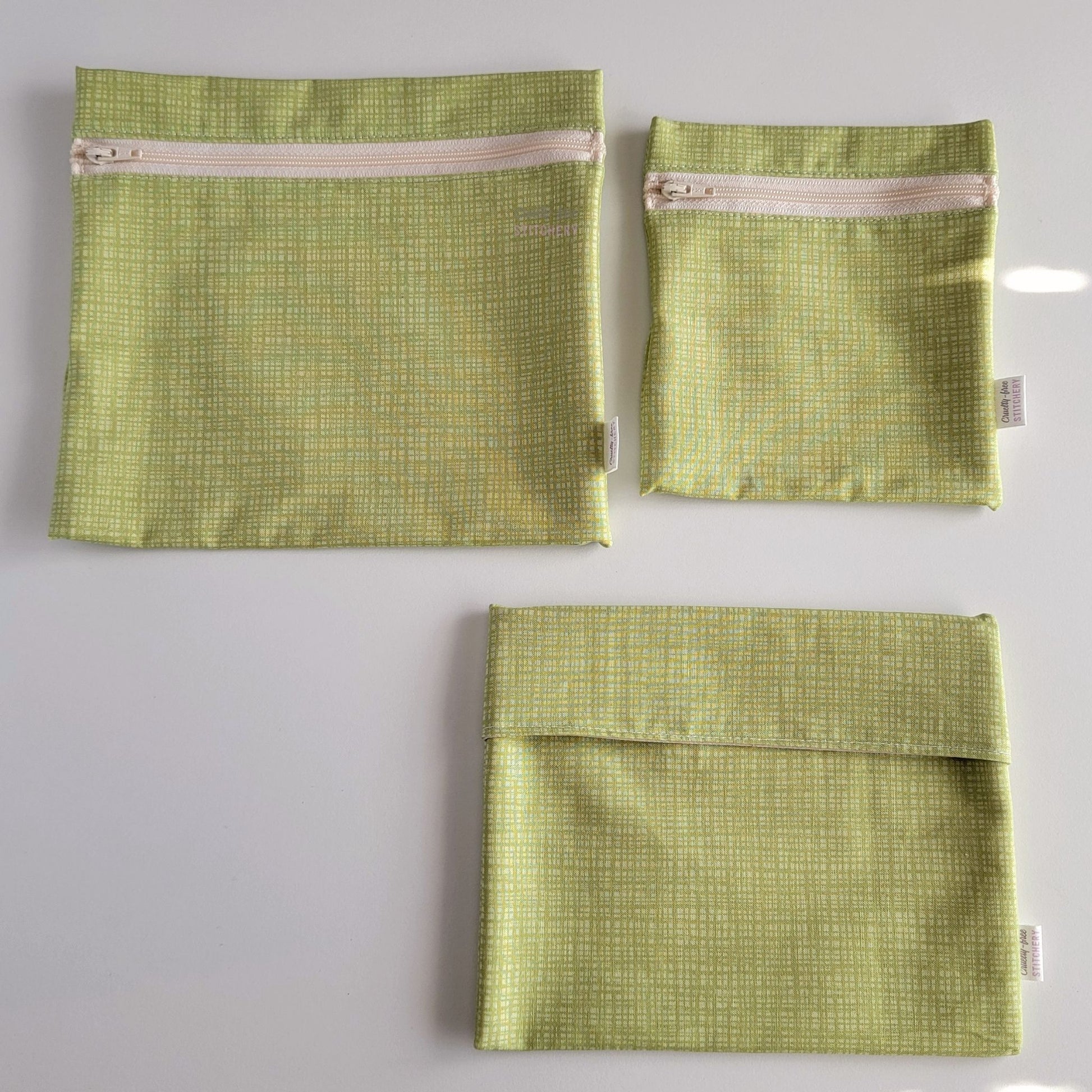 Three Light Green Texture Reusable Snack Bags arranged separately to show the difference between sizes. Large Zip is not quite double the size of the Small Zip, and the Foldover is slightly smaller than the Large Zip.