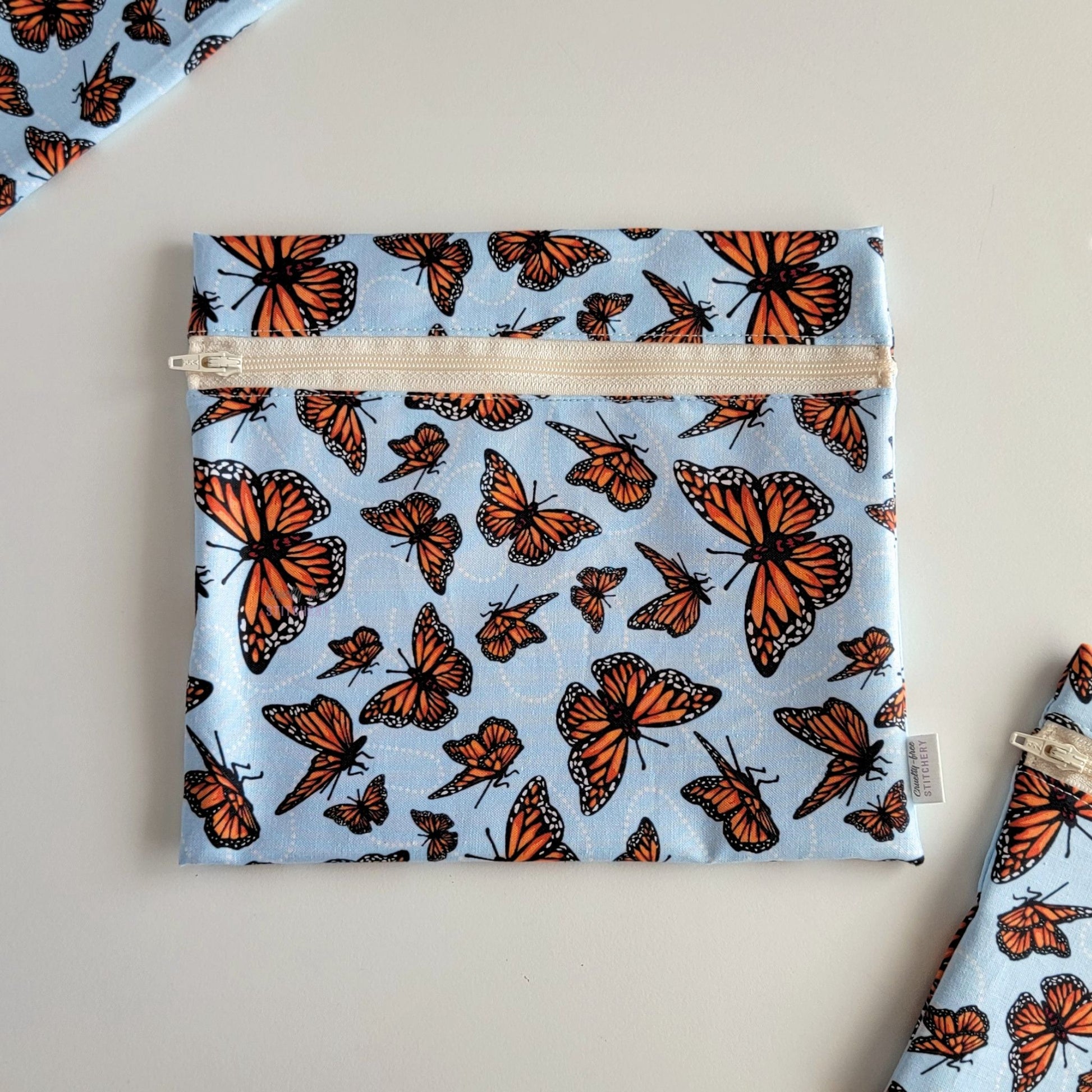 The Monarch Blue Large Zip Reusable Snack Bag, shown closed with two other bags barely visible on the edges of the photo. 