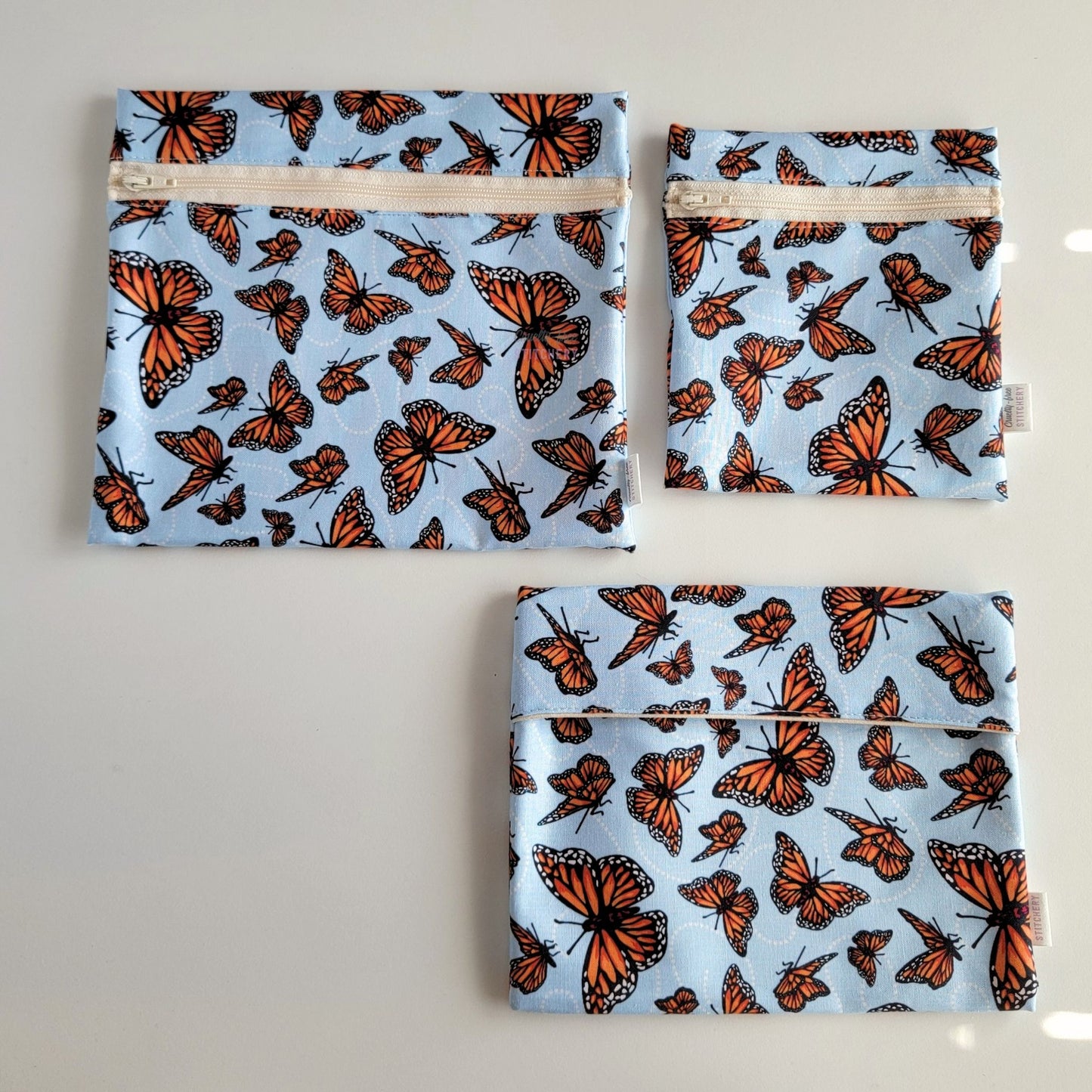 Three Monarch Blue Reusable Snack Bags arranged separately to show the difference between sizes. Large Zip is not quite double the size of the Small Zip, and the Foldover is slightly smaller than the Large Zip.
