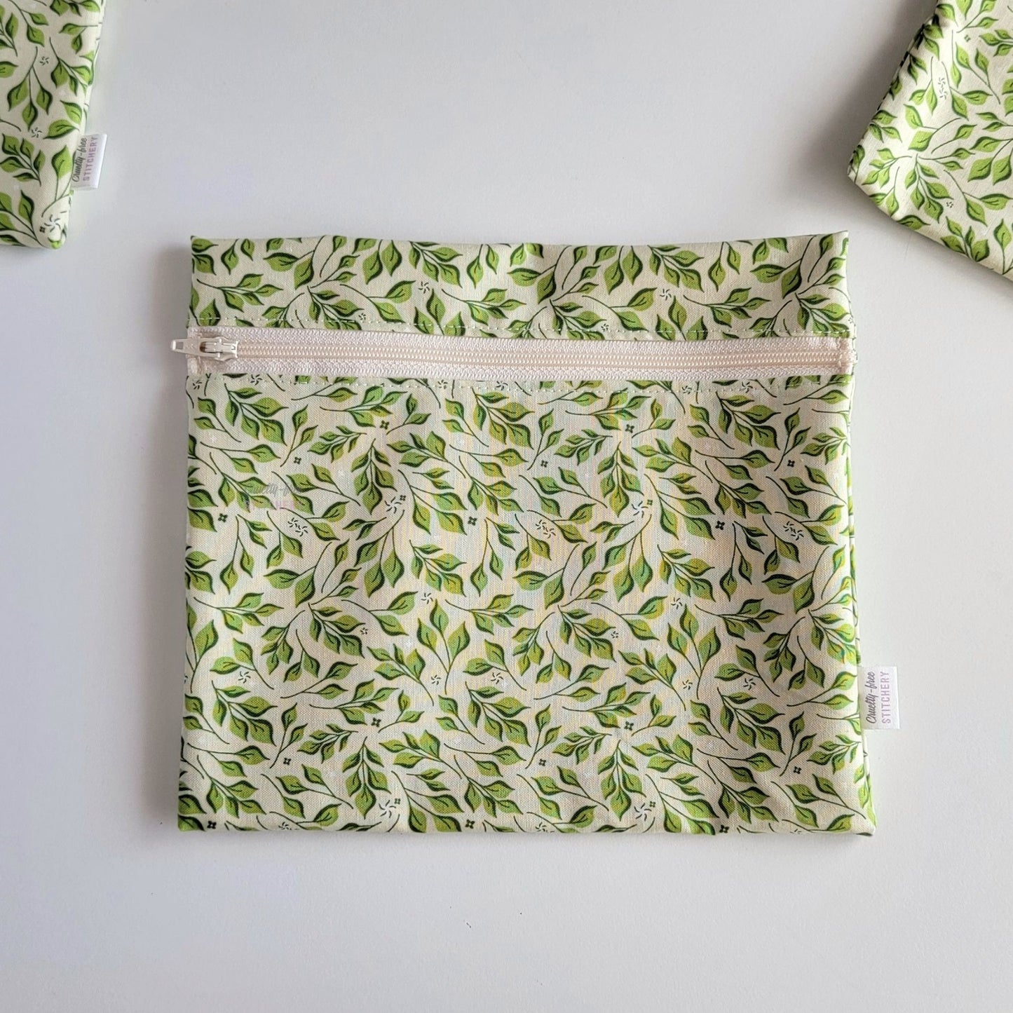 The Olive Leaves Large Zip Reusable Snack Bag, shown closed with two other bags barely visible on the edges of the photo. 
