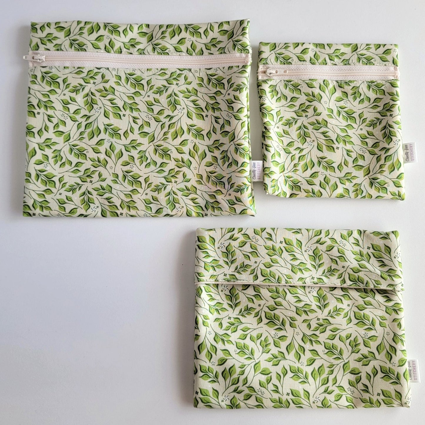 Three Olive Leaves Reusable Snack Bags arranged separately to show the difference between sizes. Large Zip is not quite double the size of the Small Zip, and the Foldover is slightly smaller than the Large Zip.
