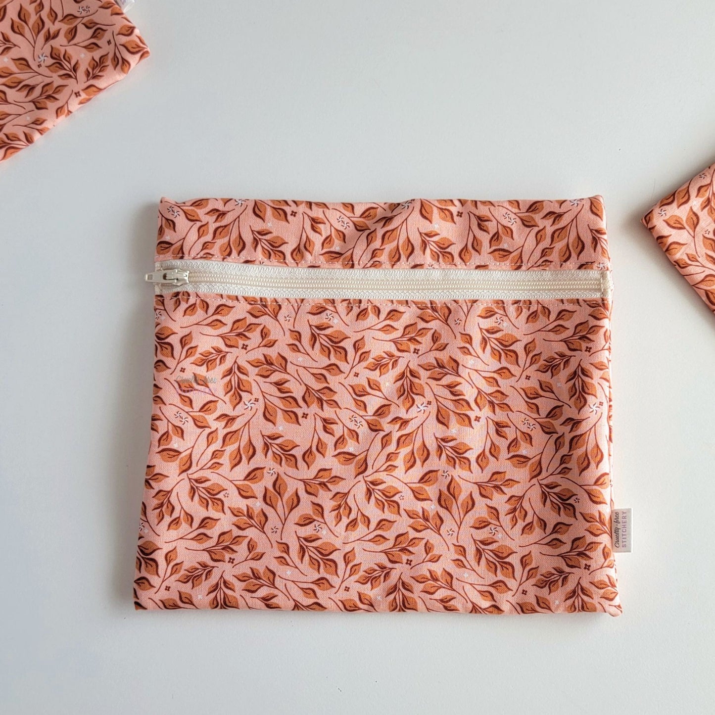 The Pink Leaves Large Zip Reusable Snack Bag, shown closed with two other bags barely visible on the edges of the photo. 