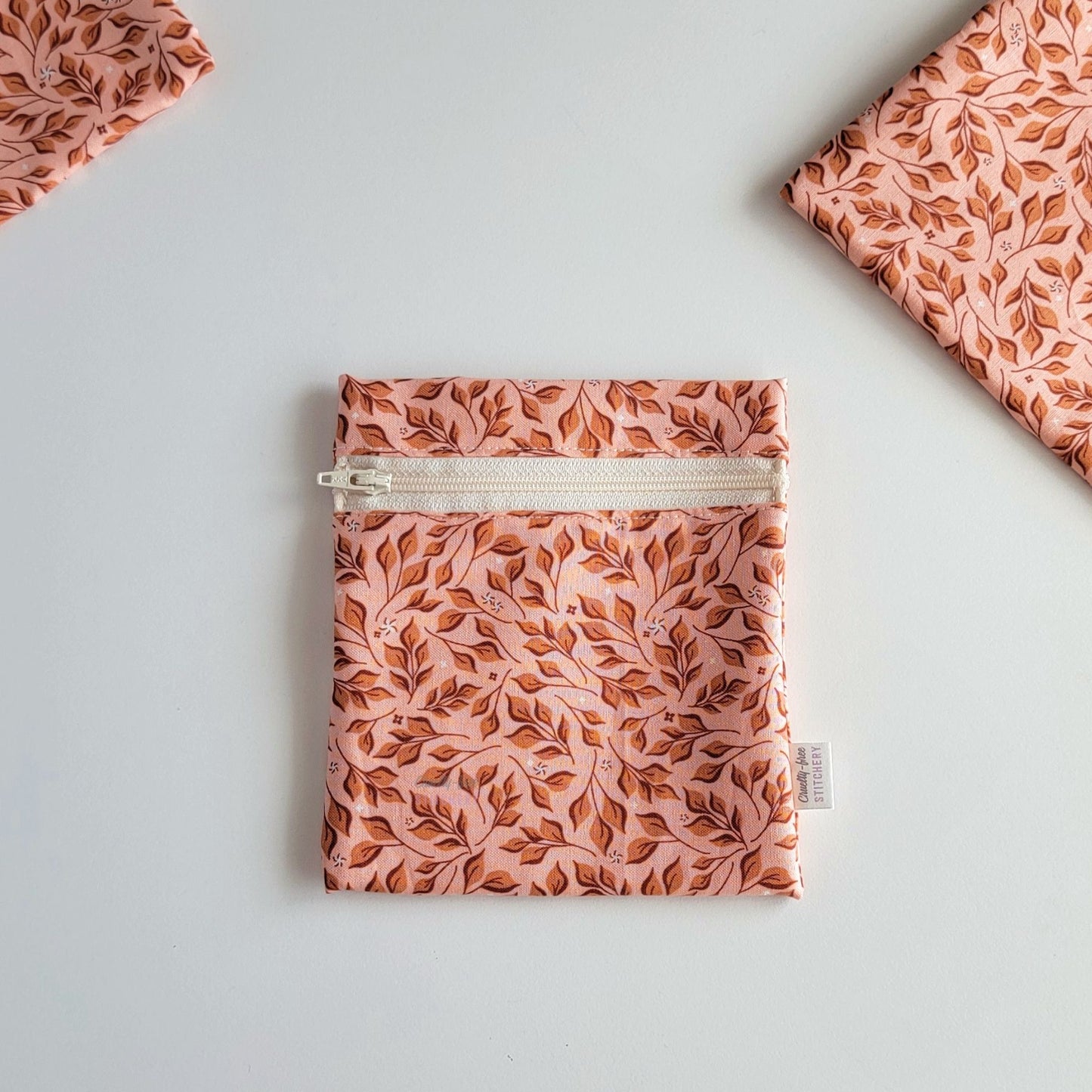 The Pink Leaves Small Zip Reusable Snack Bag, shown closed with two other bags barely visible on the edges of the photo. 