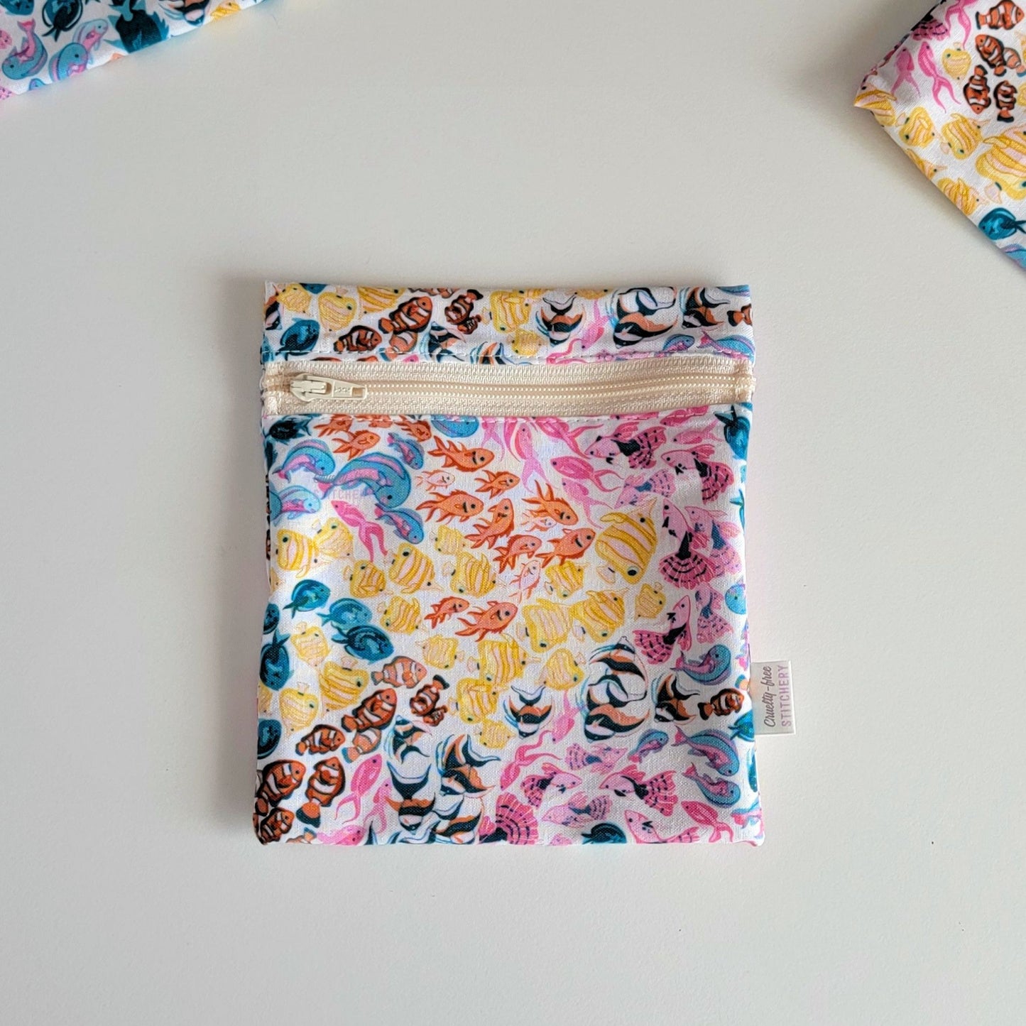 The colorful reef Small Zip Reusable Snack Bag, shown closed with two other bags barely visible on the edges of the photo. 