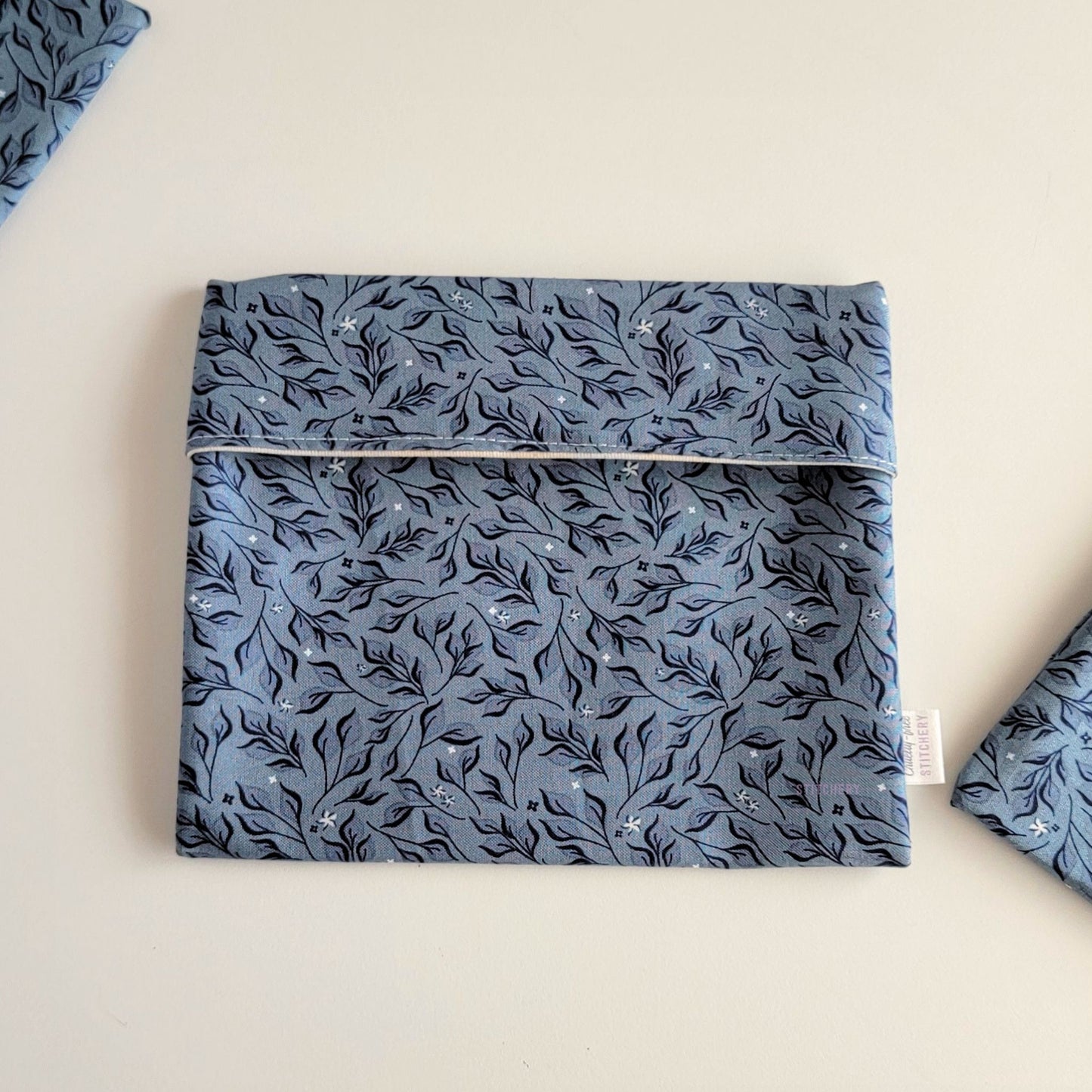 The Stone Leaves Foldover Reusable Snack Bag, shown closed with two other bags barely visible on the edges of the photo. 