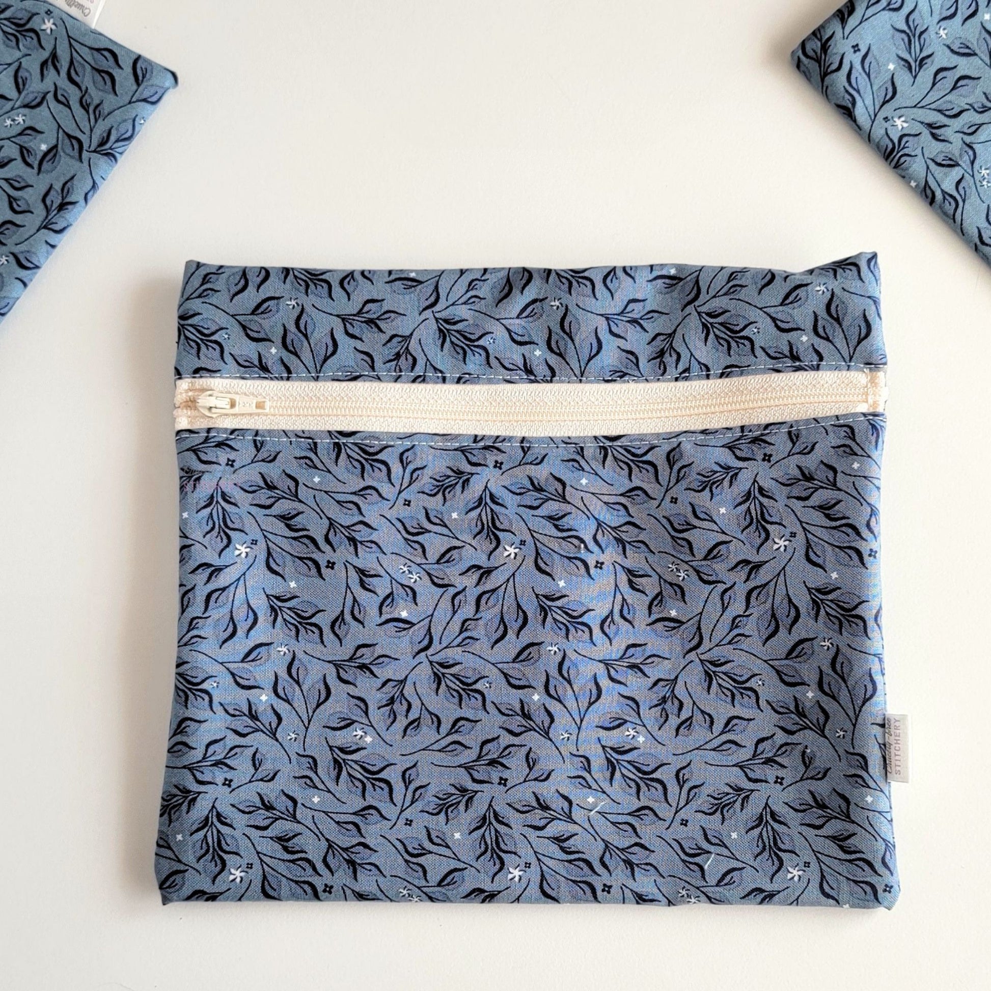 The Stone Leaves Large Zip Reusable Snack Bag, shown closed with two other bags barely visible on the edges of the photo. 
