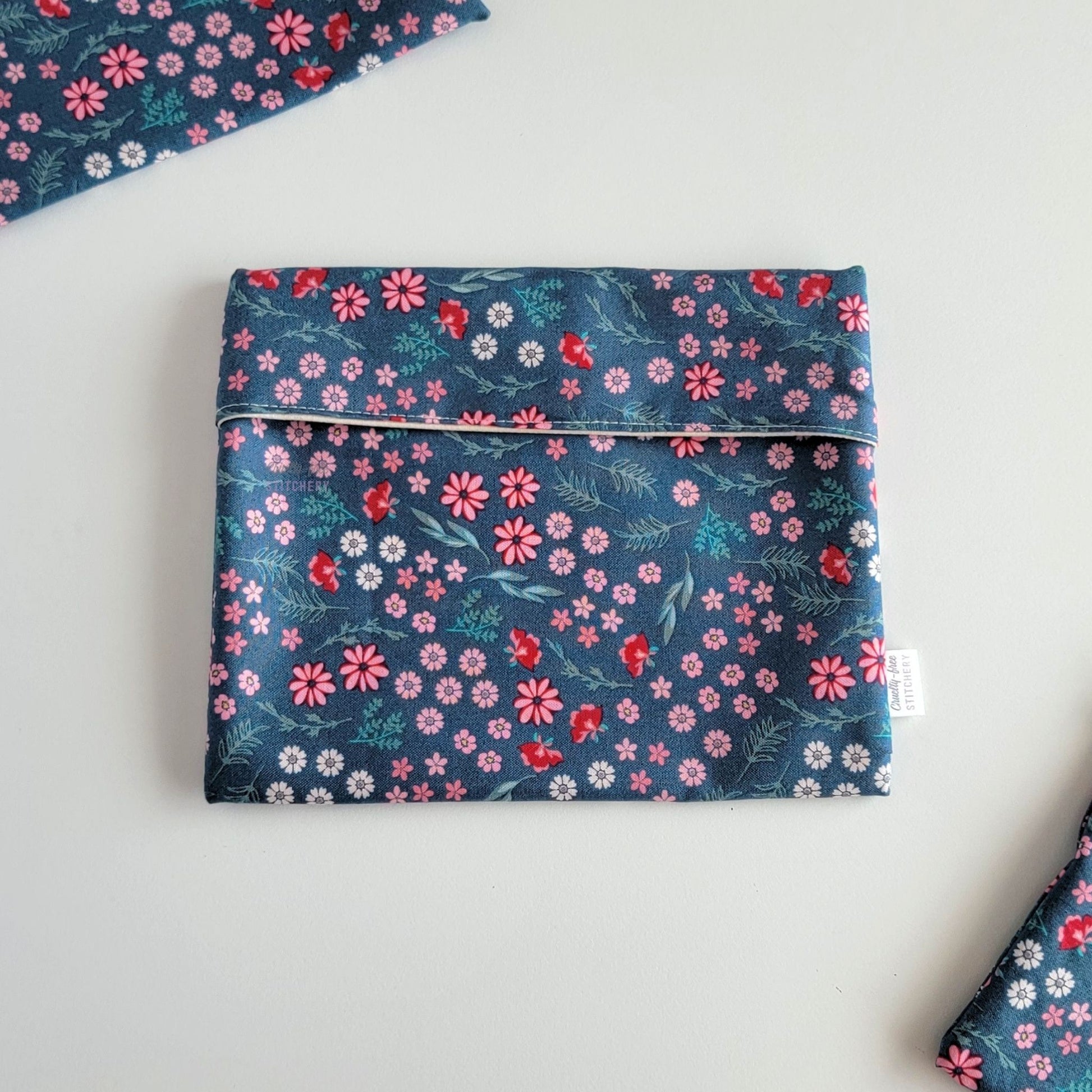 The Teal Pink Floral Foldover Reusable Snack Bag, shown closed with two other bags barely visible on the edges of the photo. 
