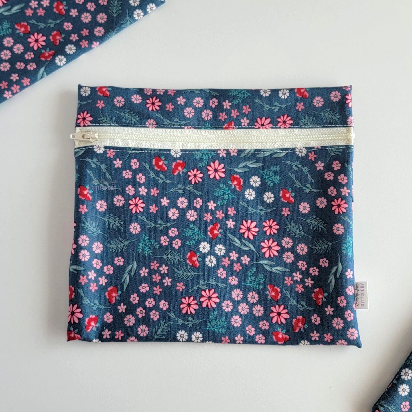 The Teal Pink Floral Large Zip Reusable Snack Bag, shown closed with two other bags barely visible on the edges of the photo. 