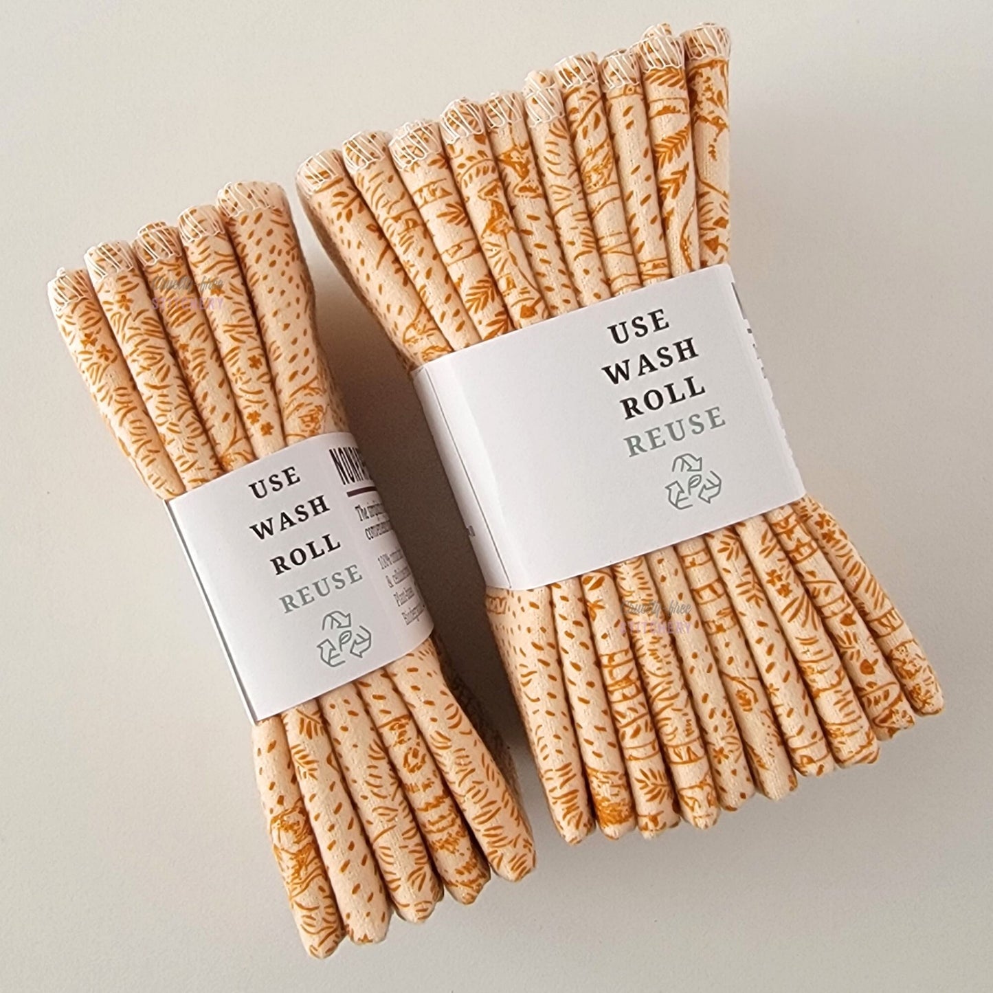 Two packages of the Acorn Woodland NonPaper Towels, shown on their side to display the 5-pack and 10-packs. The side of the paper tag says "use, wash, roll, reuse" and has the recycling logo with a leaf in the center, to symbolize they are biodegradable.