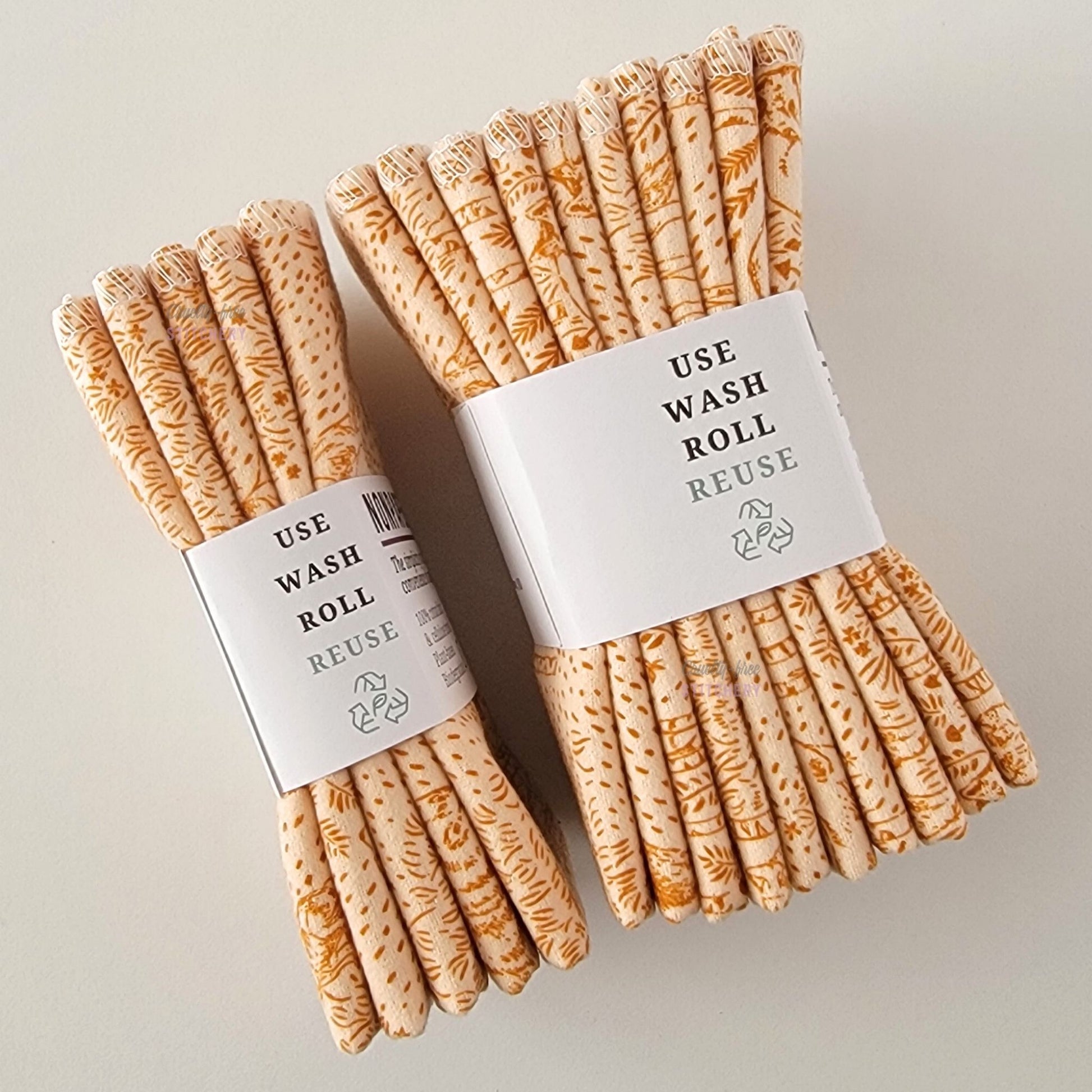 Two packages of the Acorn Woodland NonPaper Towels, shown on their side to display the 5-pack and 10-packs. The side of the paper tag says "use, wash, roll, reuse" and has the recycling logo with a leaf in the center, to symbolize they are biodegradable.