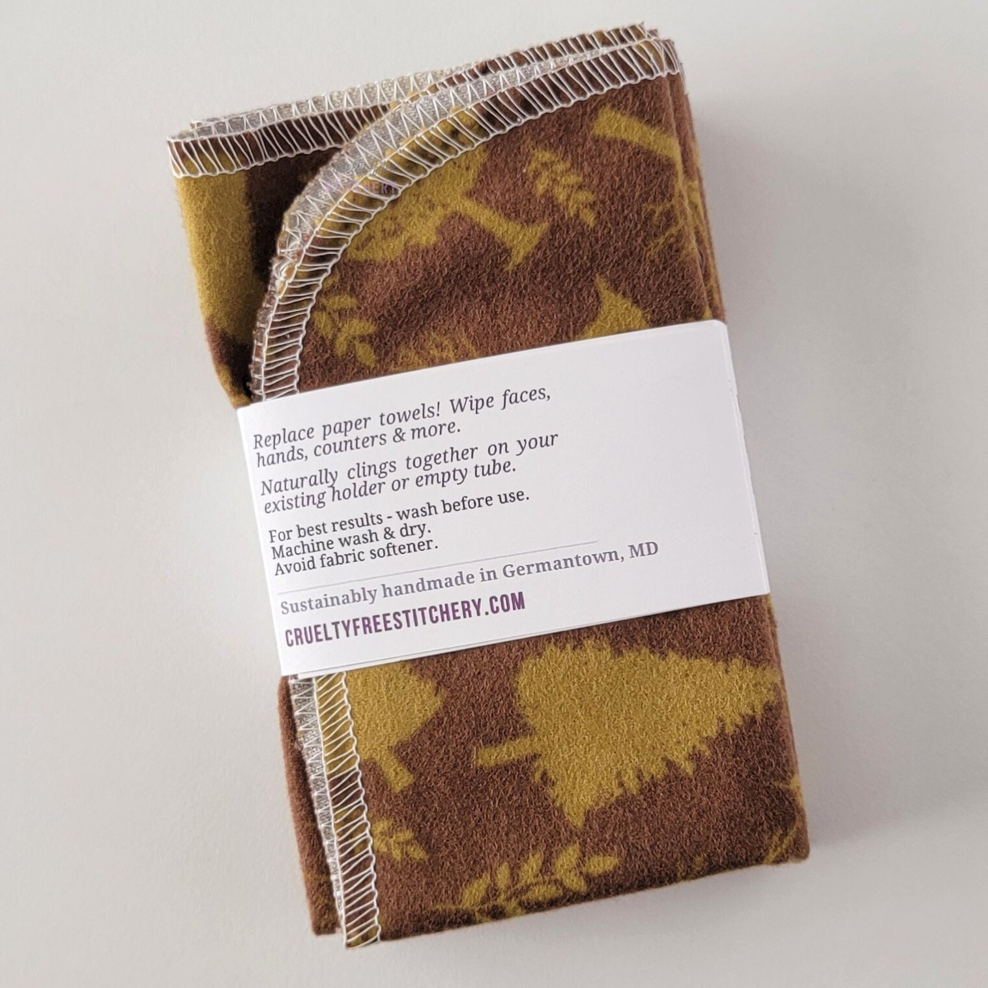 The back of a packaged bundle of the Brown Trees NonPaper Towels. The tag reads "Replace paper towels! Wipe faces, hands, counters, and more. Naturally clings together on your existing holder or empty tube. For best results - wash before use. Machine wash and dry. Avoid fabric softener. Sustainable handmade in Germantown, Maryland. CrueltyFreeStitchery dot com."