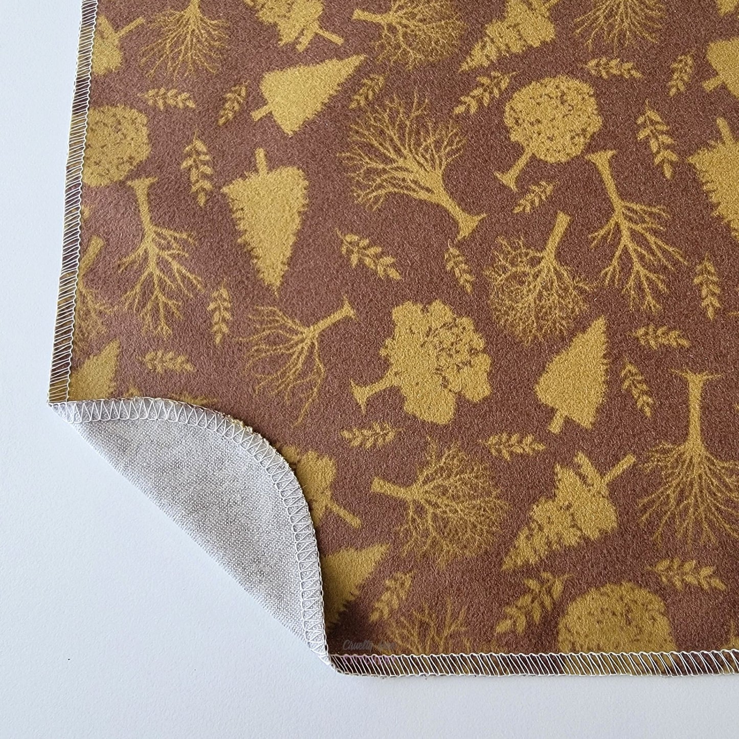 The Brown Trees NonPaper Towel, shown close-up with the bottom corner folded back to show they are unprinted on the back side, and are one layer.
